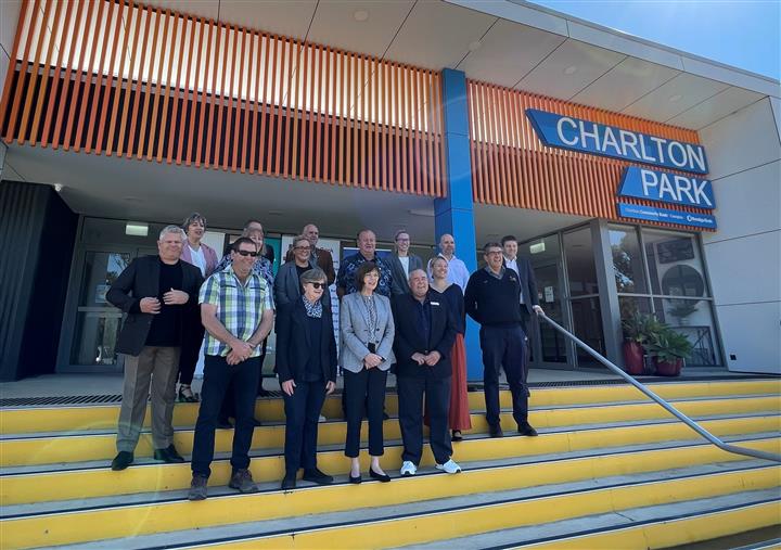 Group photo of about 20 people standing on steps at a sporting complex