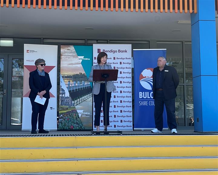 Photo of Win Scott, Chair Regional Mallee Partnership, The Hon Mary-Anne Thomas M.P., Minister for Regional Development and Cr. Daryl Warren, Buloke Shire Council Mayor standing in front of three banners from the project sponsors at Charlton Park.